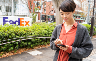 woman on mobile with FedEx truck