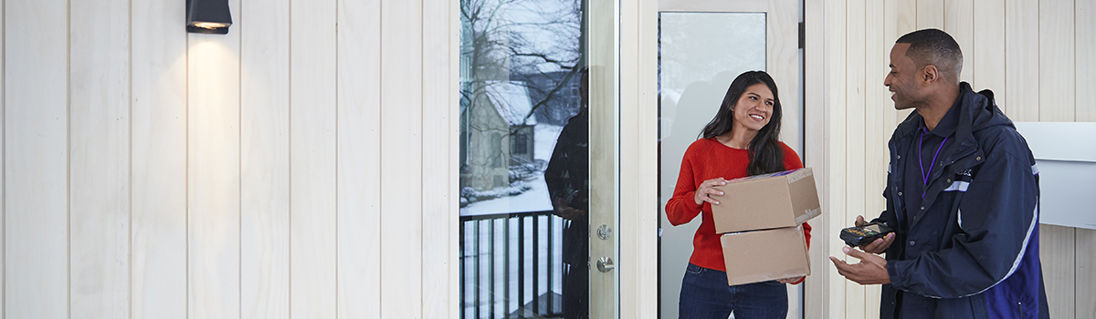 Woman in red shirt holding boxes by FedEx employee