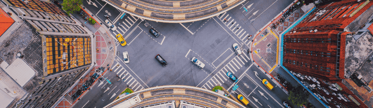 Vue aérienne d’un carrefour urbain animé, avec des voies ferrées surélevées incurvées et des bâtiments aux alentours.