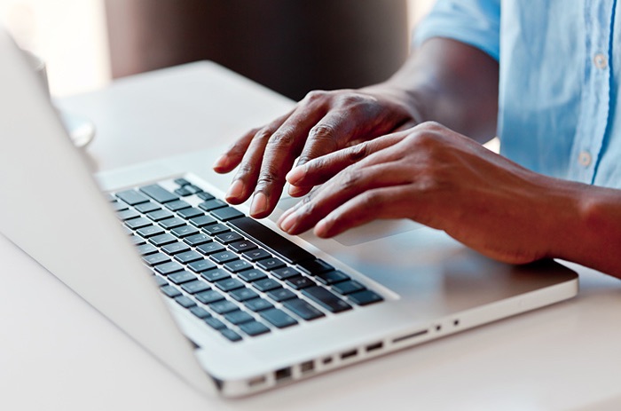 Close-up on male hands typing on laptop keyboard.