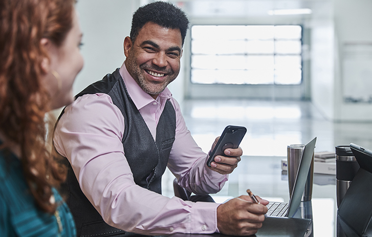 Smiling man with phone talking to woman