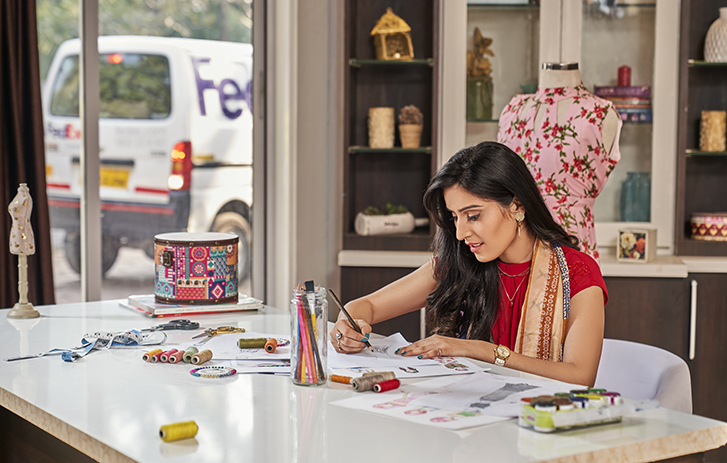 Designer working at a desk with a FedEx van outisde the window