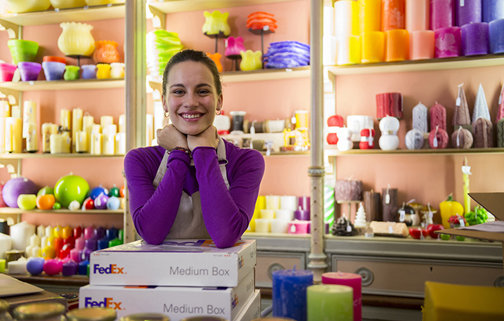 Shop clerk smiling with elbows on a couple of FedEx boxes