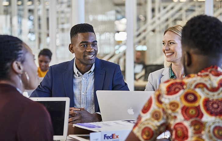 coworkers talking and smiling with a FedEx box