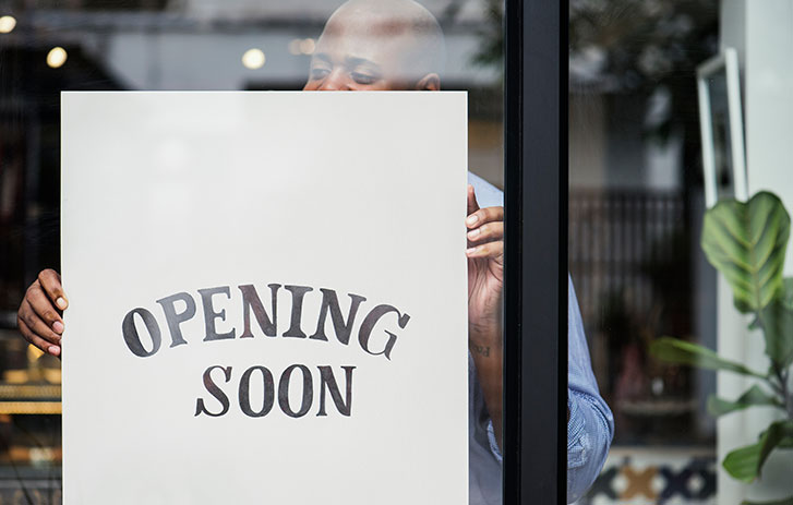 Man putting opening soon sign on store window