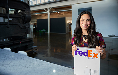 A young woman brings a FedEx envelope to a service counter. 