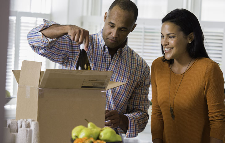 two people packing wine into brown boxes