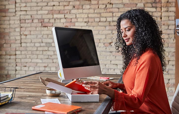 Woman sitting at desk opening up package