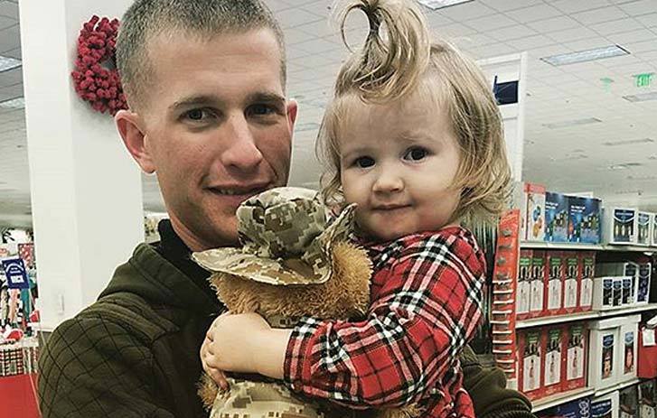 A photo of Scott Baum, founder of ZZZ Bears, holding a little girl with a teddy bear that's wearing an Army uniform