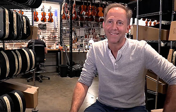 A photo of a Fiddlershop's Pierre Holstein surrounded by violins and violas