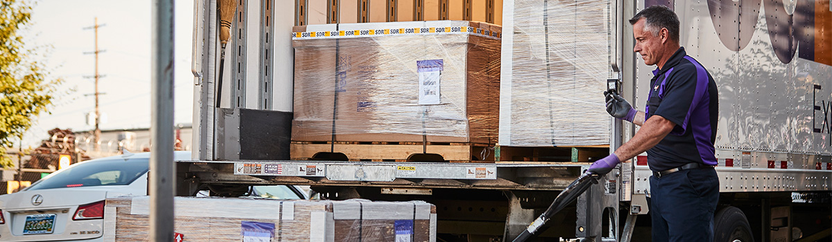 A FedEx team member raising a pallet onto a truck.