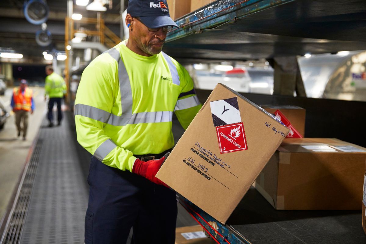 A FedEx team member holding a package with labels on it.