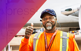 Un miembro del equipo cerca de un avión de FedEx, haciendo la señal de pulgar hacia arriba. 