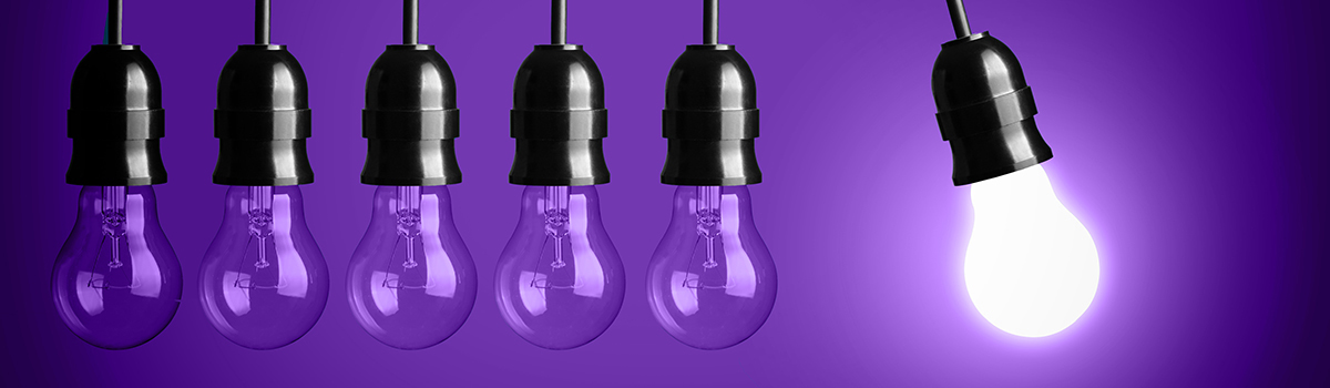 A row of lightbulbs against a purple background, the last one illuminated