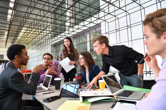 Personas trabajando y platicando alrededor de una mesa