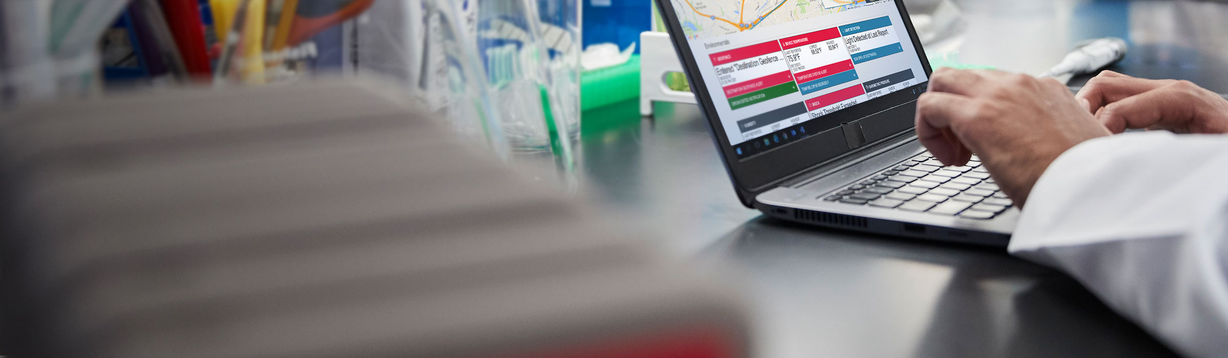 Person uses laptop in a lab with microscopes in background