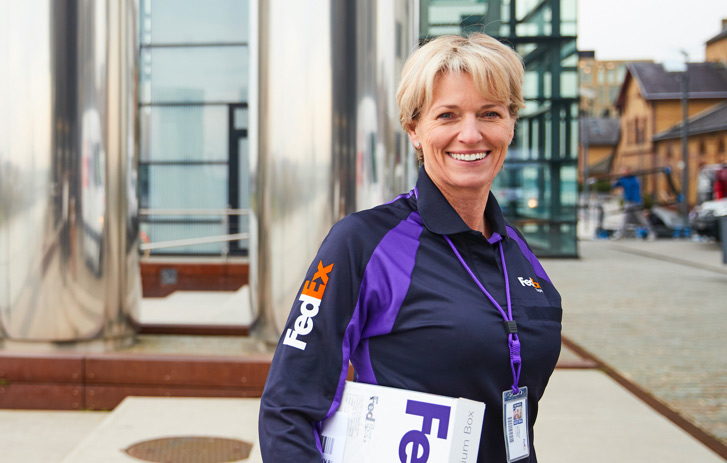 smiling fedex courier holding white fedex box