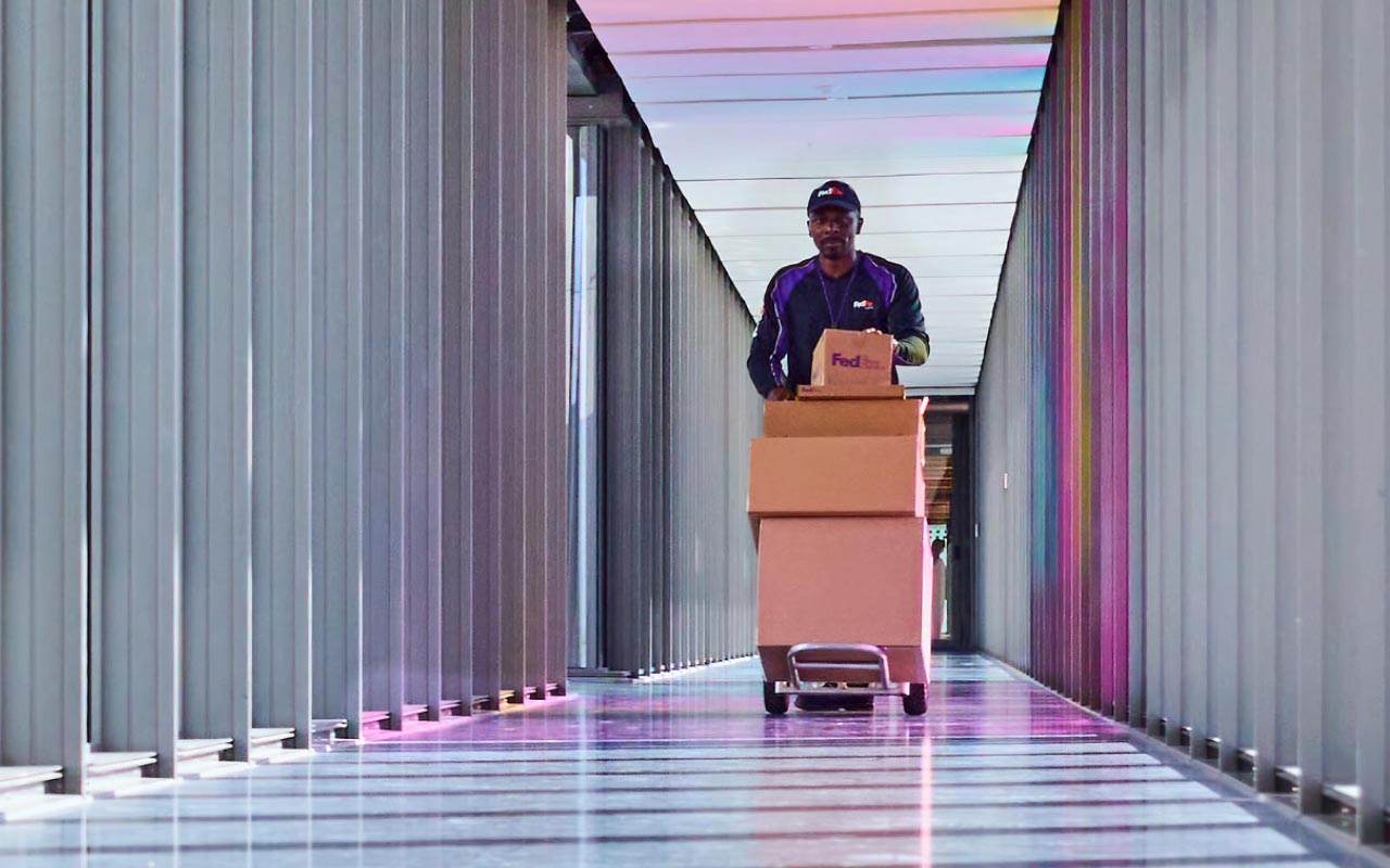 A FedEx team member pushing boxes down a hallway.