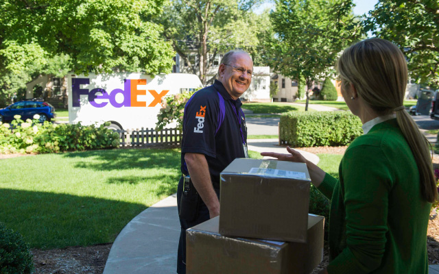 A FedEx team member delivering a package with a smile.