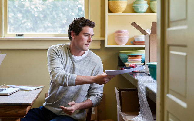 A person putting a stack of papers on a desk.