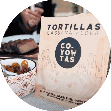 A group of people having a meal with a bag of tortillas on the table