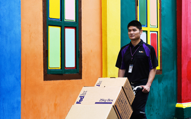 FedEx team member pushing a dolly full of packages.