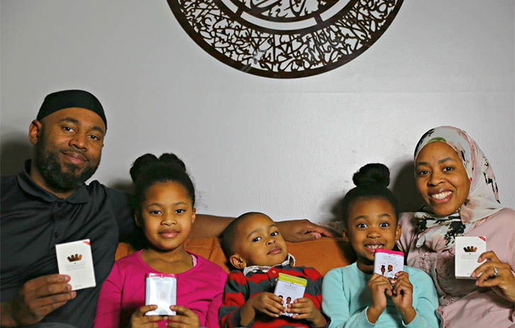 A family of five sitting together while they each hold up a box of bandages