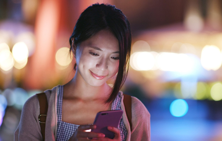 lady smiling while looking at her mobile phone