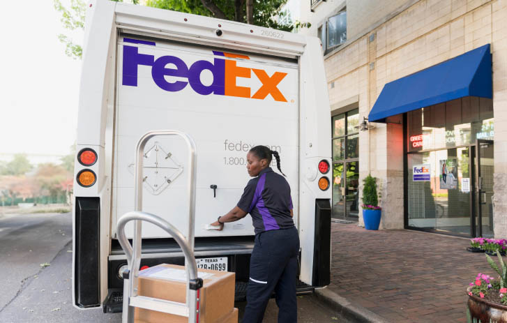 A FedEx team member opening the back door of a delivery truck.