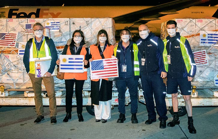 FedEx team members in front of pallets of vaccines.