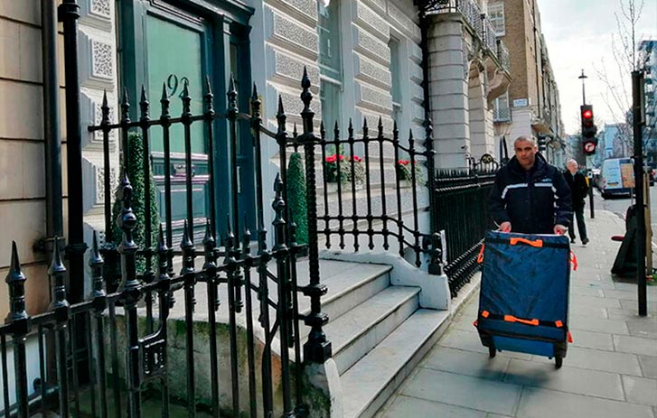 courier pushing packages on sidewalk